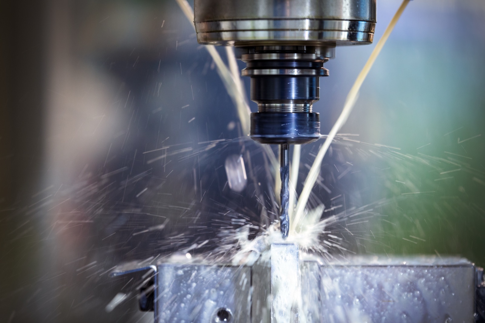 Macro detail of CNC drilling, sparks visible, on a precision metal bike component.