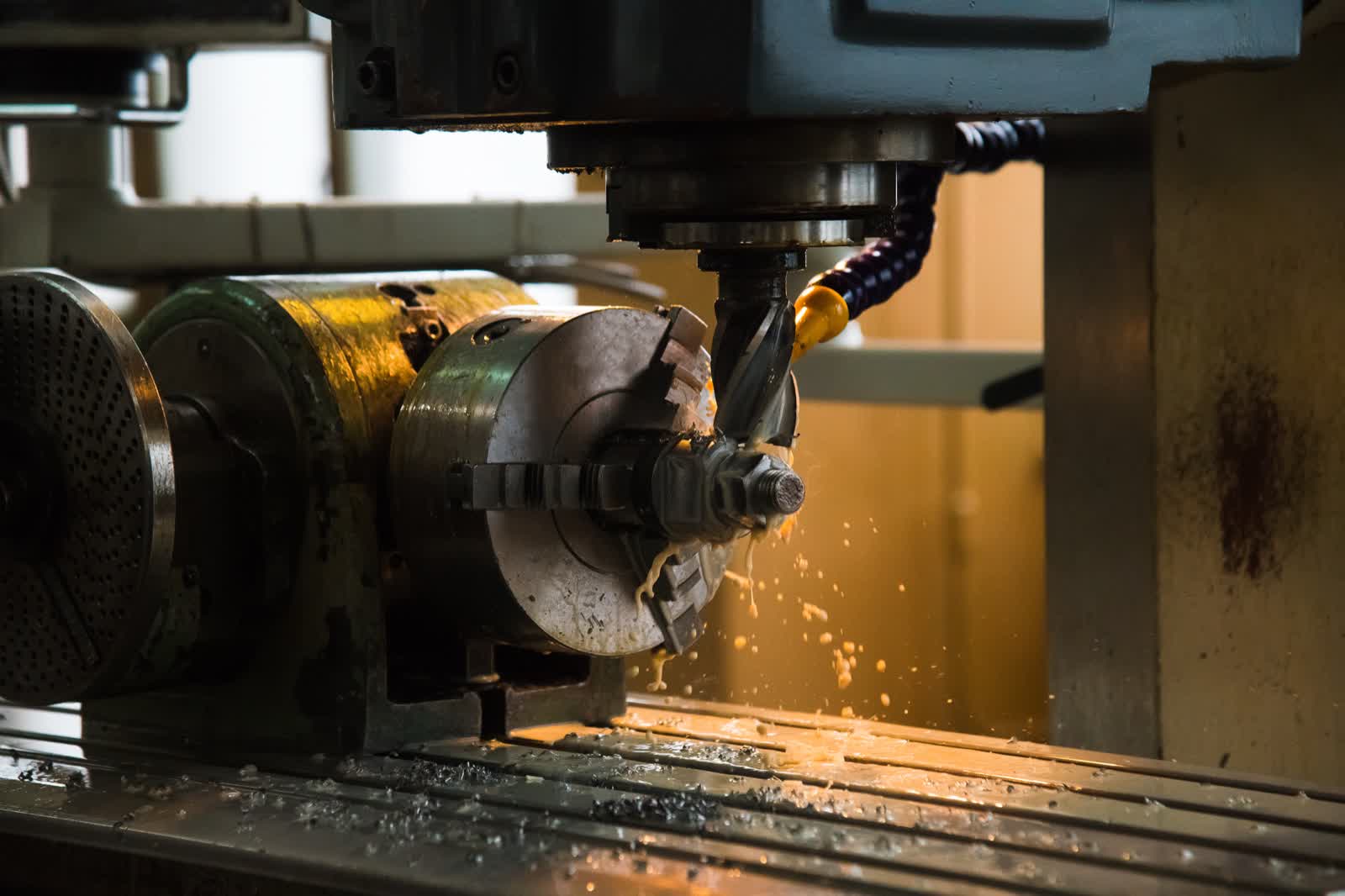 CNC milling with coolant spray, cutting a precision metal component for structural hardware.