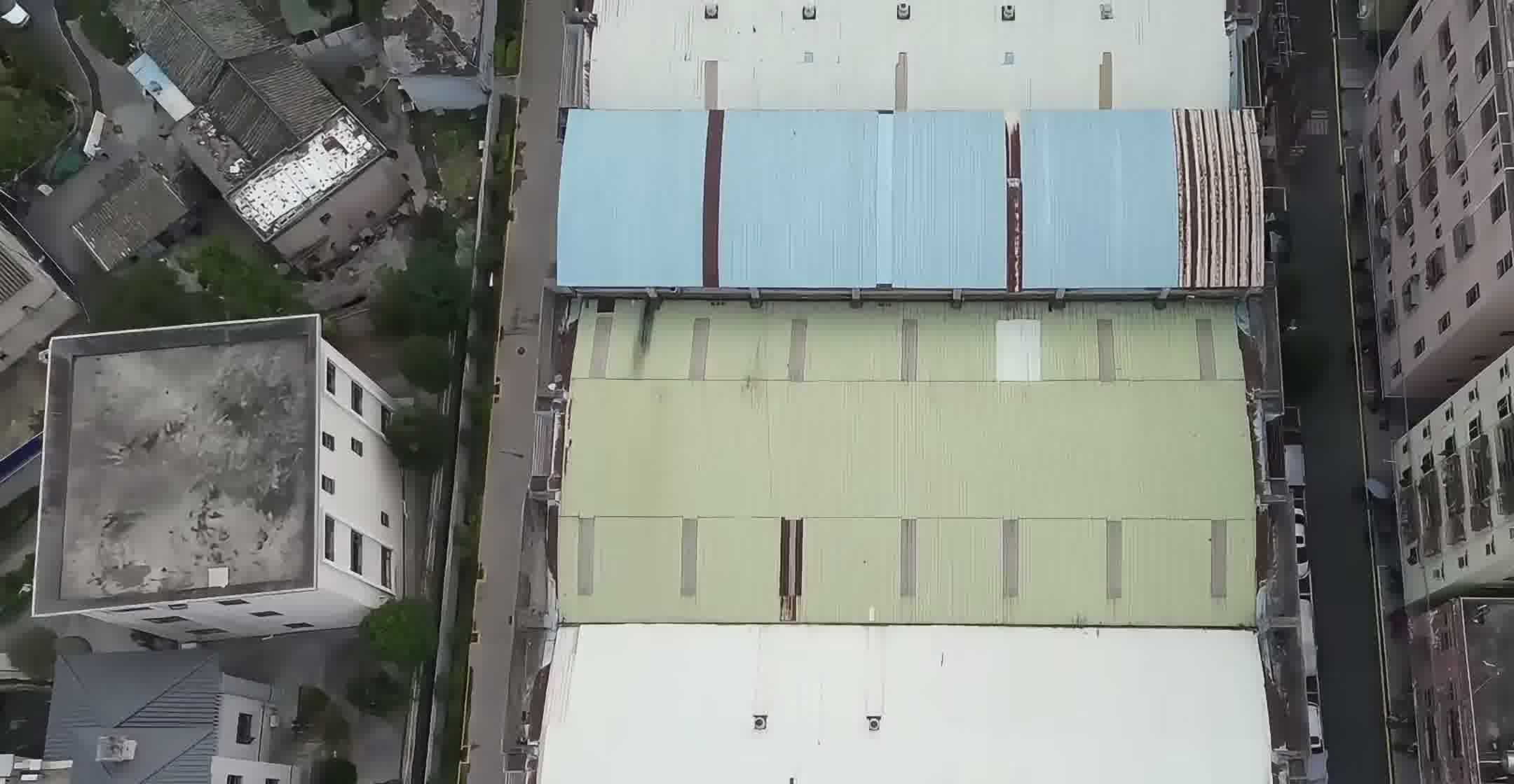 Rising drone view of the Fudakin manufacturing compound in Shenzhen, showing multiple production buildings and surrounding facilities.