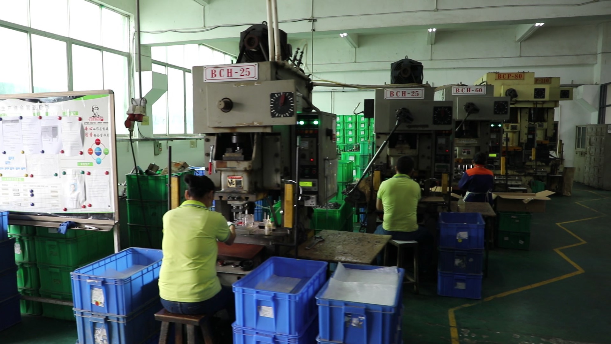 Operators working at stamping presses on the Shenzhen factory floor.